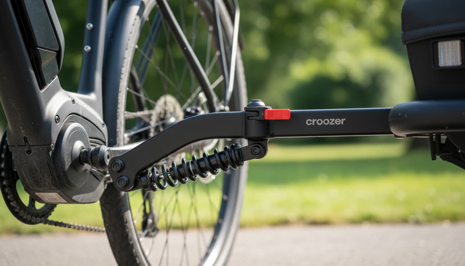 Le bras d'attelage et la suspension d'une remorque Croozer Keeke connectés à un vélo électrique dévoilent des finitions métalliques détaillées.